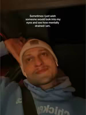 A man in a blue hoodie and a white beanie is seated in a car, looking up with a contemplative expression. Text overlays on the image reflect introspective thoughts.