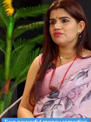 The cover image features a woman in a pink saree, sitting indoors with a blurred green leafy background. Text at the bottom says "Two powerful money remedies."