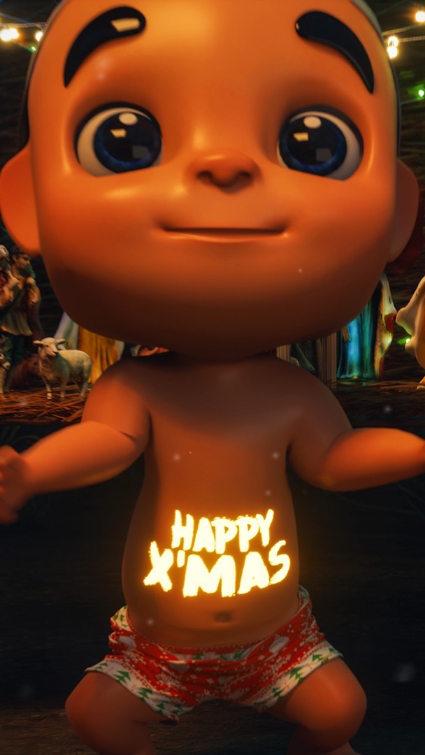A close-up shot of an animated baby figure with a round face, large blue eyes, and light brown skin. The baby is wearing red and white Christmas-themed shorts. The text "HAPPY X'MAS" is illuminated, glowing on the baby's stomach. The background is blurred and shows a nativity scene, with parts of other figures visible, suggesting a Christmas crib scene.