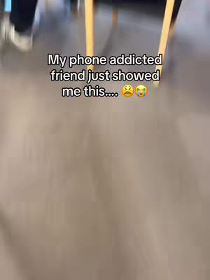 The cover image features a blurred interior scene, with a floor and partial view of legs and a table. The text overlay reads, "My phone addicted friend just showed me this...." followed by crying and sad face emojis.