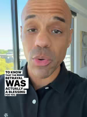 A bald, light-skinned man with dark facial hair is centered in the frame, speaking directly to the camera. He wears a black collared shirt, and the background softly reveals windows with an obscured outdoor view. Overlaid on the image is a rectangular text box with the words 'TO KNOW THAT THE BETRAYAL WAS ACTUALLY A BLESSING FOR YOU.' The overall composition suggests a personal address, with the text providing the central theme.