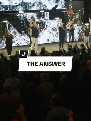 The cover image shows the stage of a church service. On the foreground, there is a white rectangle with black text that reads 'THE ANSWER'. Behind the rectangle, people are on the stage with their hands up, and in the background is a stage screen with light effects.