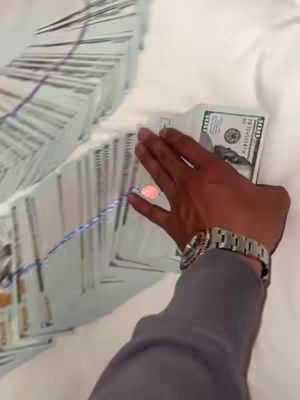 The cover image shows a hand holding a stack of hundred-dollar bills; another large stack of bills is visible in the background, all on a white surface.