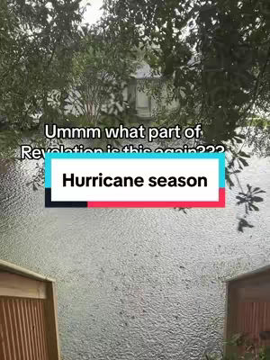 The image shows a rainy scene with a wooden fence in the foreground on the bottom left and right corners, with the rain creating a blurred background. Overlaid is a text box with the words "Hurricane season". Above the text and in the background slightly obscured by the rain and tree branches, appears to be a house or large building.