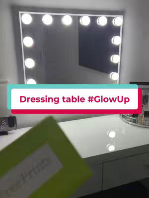 The cover image showcases a dressing table with a large mirror illuminated by surrounding light bulbs. A green item obscures the lower area, a digital clock rests on the table's surface, and the overall design is modern and chic.
