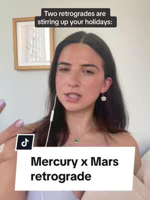 A woman with dark hair and fair skin speaks towards the camera, in front of her is a floating white box with the text "Mercury x Mars retrograde". The background is a soft white wall with a framed picture on it.