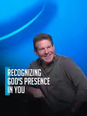 A man with short, dark hair smiles broadly in front of a blue gradient background. Text overlayed on the left reads 'Recognizing God's Presence In You'. The man is wearing a gray long-sleeved shirt, and the lighting is focused on his face, highlighting his expression.