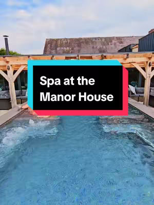 The cover image shows an outdoor spa with a swimming pool, surrounded by wooden structures under a cloudy sky. A text overlay in a rectangular box reads "Spa at the Manor House."