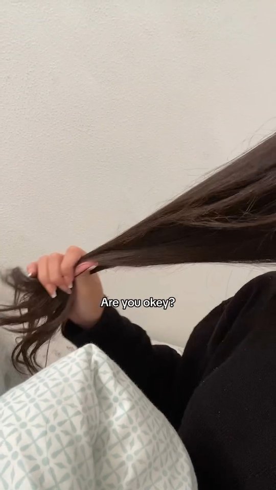 The cover image shows a person's hand holding up a length of very long, dark hair, with 'Are you okay?' overlaid on the bottom right, with a neutral white background and soft natural light.