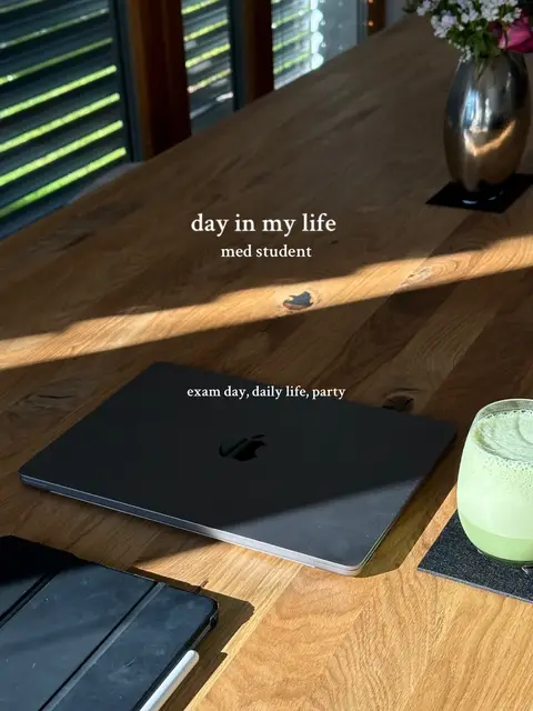 A top-down shot of a wooden table with a laptop, iPad, and a green drink in a glass. There are flowers in a vase in the background. Text overlays the image: 'day in my life med student', and 'exam day, daily life, party'.