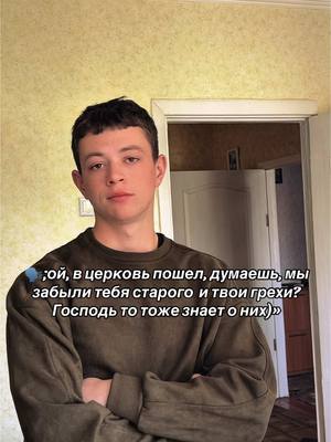 A young man in a dark green sweater stands in what appears to be a living room. The background is a light yellow wall and a partially visible door. Text overlays are visible on the image.
