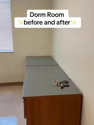 The cover image shows a dorm room corner with an empty table against a wall. A window with blinds appears on the wall to the left. On the tabletop sit a few items. The walls are beige.