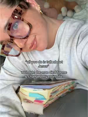 A selfie-style shot featuring a woman with glasses holding a Bible in front of her. Text overlays the image, and the woman appears to be in a casual setting. The lighting is soft and natural.