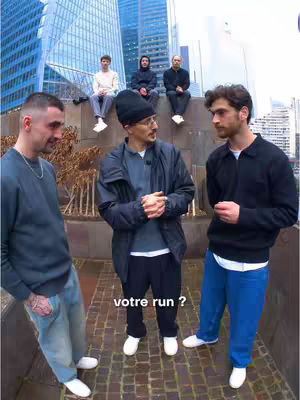 The cover image shows a group of men in an outdoor setting with tall buildings in the background. Three men are standing in the foreground, with a man in the center wearing a black beanie. Two other men are on the left and right, and a few more are sitting on a ledge in the background.