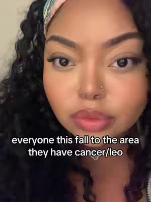A close-up selfie of a woman with long, dark, curly hair, a nose ring wearing a hairband. The background is out of focus.
