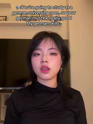 A young woman with dark hair and fair skin is centered in the frame, looking directly at the camera with a slightly open mouth. She is wearing a black top. Above her head, text overlays state, "You're going to study at a german university soon, so your german must be really good My german skills:"