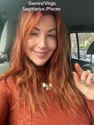 A woman with red hair smiles from the driver's seat of a car, with text overlays indicating zodiac signs.