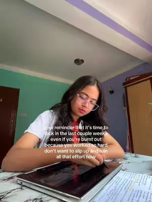 The cover image shows a young woman wearing glasses in a home study environment. She is sitting at a desk with a laptop open, a pen in her hand, and papers. Text overlay with the reminder is above the laptop.