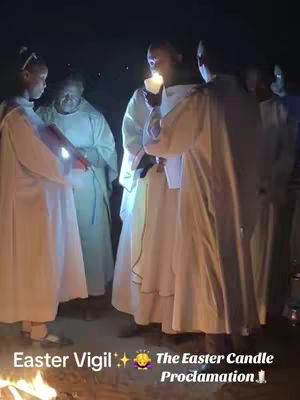 The cover image shows a group of people dressed in white robes holding candles in a low-lit setting. The image is dark, suggesting it is night. In the foreground, a fire is visible.