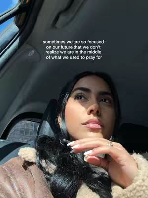 A selfie taken from inside a car. The creator, a woman with long, dark hair, is looking up and right with a contemplative expression. The text overlayed on the image provides a message about focusing on the future. The background is the interior of a car, with the windshield and parts of doors.