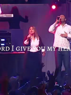 The cover image shows a live performance scene on a stage. A woman in a white shirt and black skirt is singing into a microphone, accompanied by a man in a white patterned shirt. Both are holding microphones. The word "Lord" is partially visible in white over them.