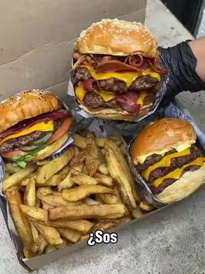 The image displays a box filled with fast food: three burgers with sesame seed buns, cheese, and beef patties, and a large pile of french fries. The burgers are attractively presented, and the fries are golden-brown. The text overlay '¿Sos' is in the lower center, written in white sans-serif font with a black box background.