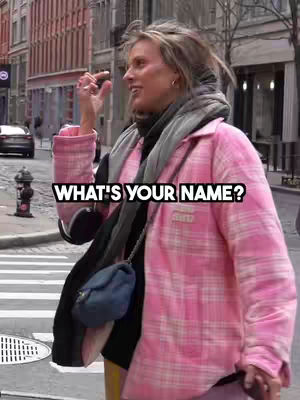 A woman in a bright pink plaid jacket stands angled to the left on a city street. She's making a hand gesture as though she is holding something small, with the text overlayed in a bubble.