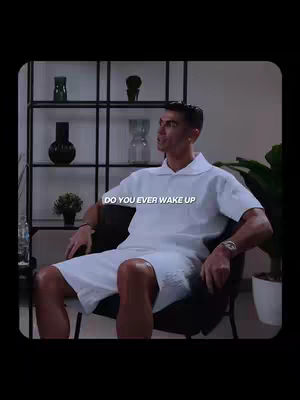 The image shows Cristiano Ronaldo seated in a stylish room, dressed in a white outfit against a neutral background. Text overlay reads 'DO YOU EVER WAKE UP'. The lighting, setting and pose indicates a motivational content.