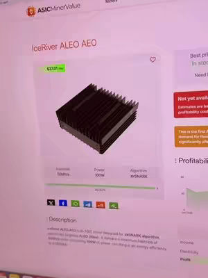 A computer screen displaying a webpage with information about an IceRiver ALEO AEO, a digital mining device. The screen is white with mostly black text, and there is a grayscale image of the device in the middle of the frame. Various metrics are listed with icons on the bottom.