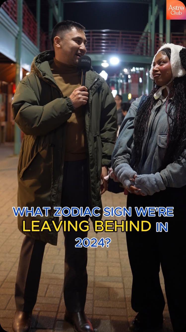 The cover image is a street interview scene at night with two people facing each other. The interviewer, a man with short dark hair wearing a green coat, holds a microphone. Opposite him is a woman in a denim jacket and a hat, who appear to be the subject of the interview. The background is a blurry street scene with lights and other people faintly visible. A text overlay in the center displays the question.