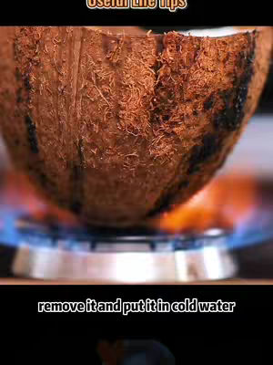 The image shows a split coconut shell placed over a blue gas flame, suggesting a heating process. Below this, at the bottom of the image, is a black background and white text that is part of the overlay.