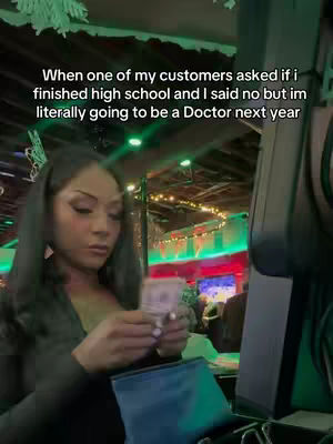A woman, lit by warm interior lighting, is seen behind a bar or counter, holding some bills and a blue card holder. Text overlayed on the top of the screen.