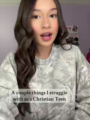 A woman with long wavy brown hair is centered in a medium shot. She's talking, with a slight smile, wearing a gray and white tie-dye patterned long sleeve shirt. The background is slightly blurred, and text overlayed on the image reads: "A couple things I struggle with as a Christian Teen."