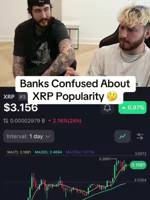 Two men are in the frame. One man in a black cap and t-shirt looks to the left, the other man, with blonde hair, looks directly ahead. An overlay shows scrolling stock market data.