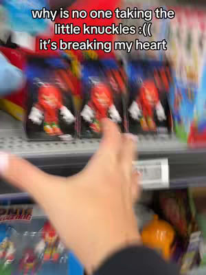 The image shows a hand of a person reaching towards toy figurines of Knuckles the Echidna in their packaging on a store shelf. Above the figurines is text that expresses sadness that nobody is buying them. The background is out of focus, suggesting a store setting.