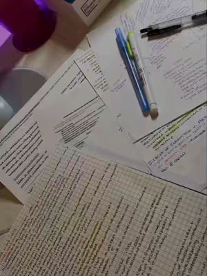 The image shows a messy desk covered in papers and notes, with pens scattered around. The lighting is neutral, and the composition is from a top-down angle.
