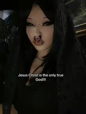 A close-up shot of a person's face, with dark hair and makeup. Text is overlaid on the image. The background is dark and indistinct.