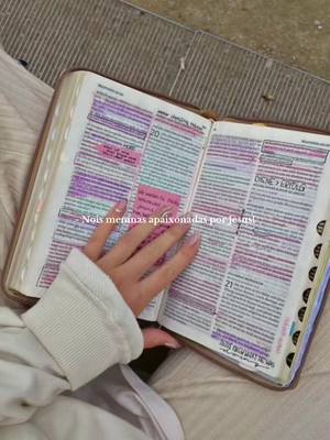 A hand with long nails rests on an open bible, with highlighted text. The image has a soft, warm color palette.