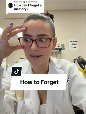 A selfie-style video cover featuring a woman with dark hair pulled back. She wears glasses and a lab coat, holding her hand up to her temple with a surprised expression. Text overlays indicate a title and a comment.