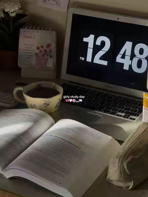 The cover image shows a cozy study setup. In the foreground, an open book with visible text is placed on a table. Beside it, there's a cup of coffee in a floral mug and a laptop displaying a clock at '12:48 PM'. A calendar and other stationery items are also visible in the background, suggesting a focused yet comfortable study environment. The lighting is warm and indirect, enhancing the cozy aesthetic.