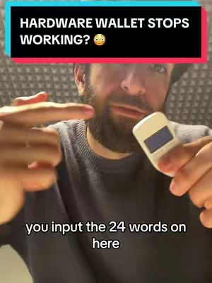 A man with a beard holds a hardware wallet, with text overlays that provide information. The image is a close-up shot emphasizing his face and the wallet. The background is a textured wall.
