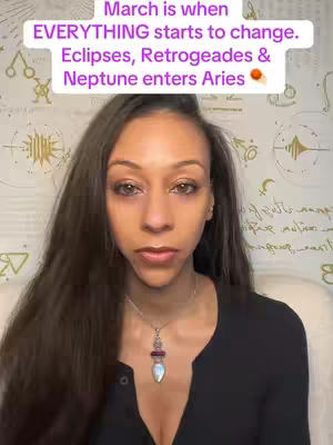 A woman with long dark hair looks directly at the camera. A text overlay is above her head, and a necklace is around her neck. The background is a blurred, neutral color.