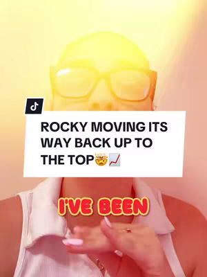 The cover image features a woman in front of a vibrant yellow and orange gradient suggesting a sunlit setting. She is wearing glasses and a white collared shirt. Overlaid text includes a white box with the message about $ROCKY going up, placed on top of her face, with another label at the bottom. The TikTok logo is present in the upper-left corner.