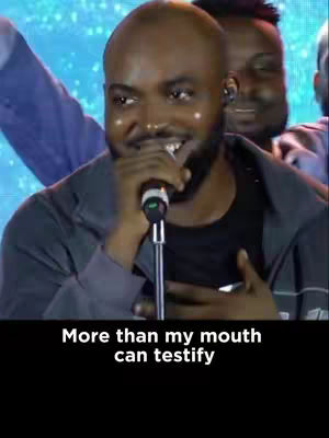 A man with a shaved head and a beard is singing into a microphone. The background has blue and purple lights. The hook text in the bottom has white text on a black background