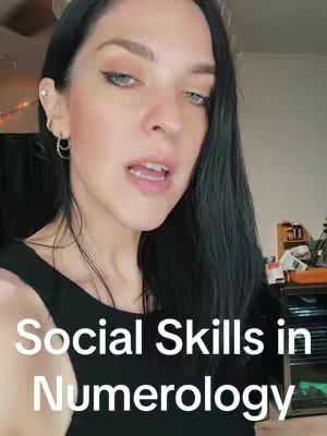 A woman with long black hair and fair skin looks towards the camera with a slight smile. Text overlayed over her includes 'Social Skills in Numerology'. The background is slightly blurred, suggesting a room setting. She wears a black top, and has hoop earrings.