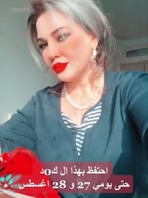 A woman with silver-streaked hair and red lipstick poses from the chest up against a background light and out of focus. She wears a navy blue top over a white and navy striped undershirt and a pearl necklace and earrings. Text in Arabic appears at the bottom of the image.