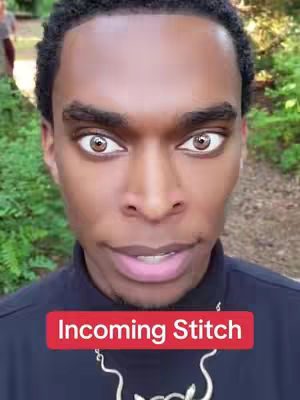 A selfie-style shot featuring a Black man with large, light-colored eyes. He is framed from the chest up, with a forest path blurred out in the background. A red banner with white text that says "Incoming Stitch" is at the bottom of the frame.