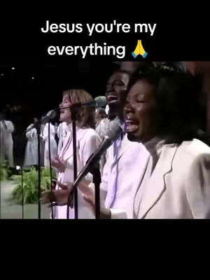 A choir with multiple people is singing on a stage. The people are dressed in white. The text overlay says "Jesus you're my everything" with a prayer hands emoji.