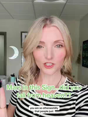 A woman with blonde hair and a black and white striped shirt speaks to the camera. Text overlaying the image reads, "Mars in this sign...did you fall from heaven??" with additional text below that reads "you are so otherworldly that people just". In the background, there are hints of an office setting.