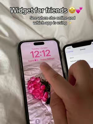 The image displays a close-up view of two iPhones on a softly lit surface. One phone's screen prominently shows a home screen with a widget displaying a friend's online status, along with the current time and date. A finger is touching the screen. The other phone is slightly out of focus. The background is a light, possibly cream-colored, fabric, suggesting a bed or a similar soft surface.